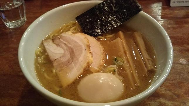 濁った茶色のスープに麺とチャーシューと煮卵と海苔とメンマが入ったラーメン